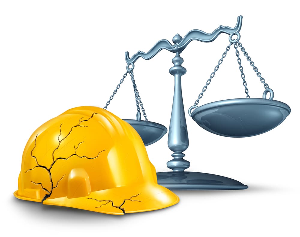 Construction Injury Law and Workplace Accident Hazards: A broken, cracked yellow hardhat alongside a scale of justice symbolizes legal protection for injured workers.