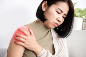 Woman holding her upper arm in discomfort