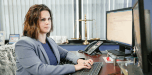 Attorney Eliza Lynch from Joye Law Firm Injury Attorneys working at a desk in an office, legal scales visible in background