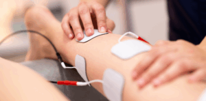 Close-up of a leg receiving physical therapy with electrode pads used for muscle stimulation treatment