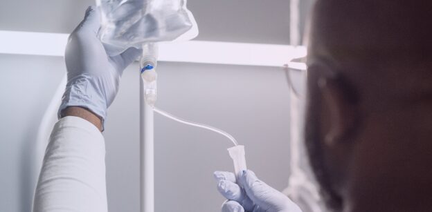 Gloved clinician adjusting an intravenous medication line